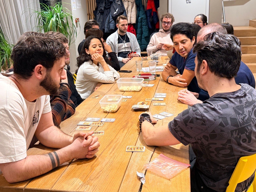 Students gathered around a table playing a language learning card game